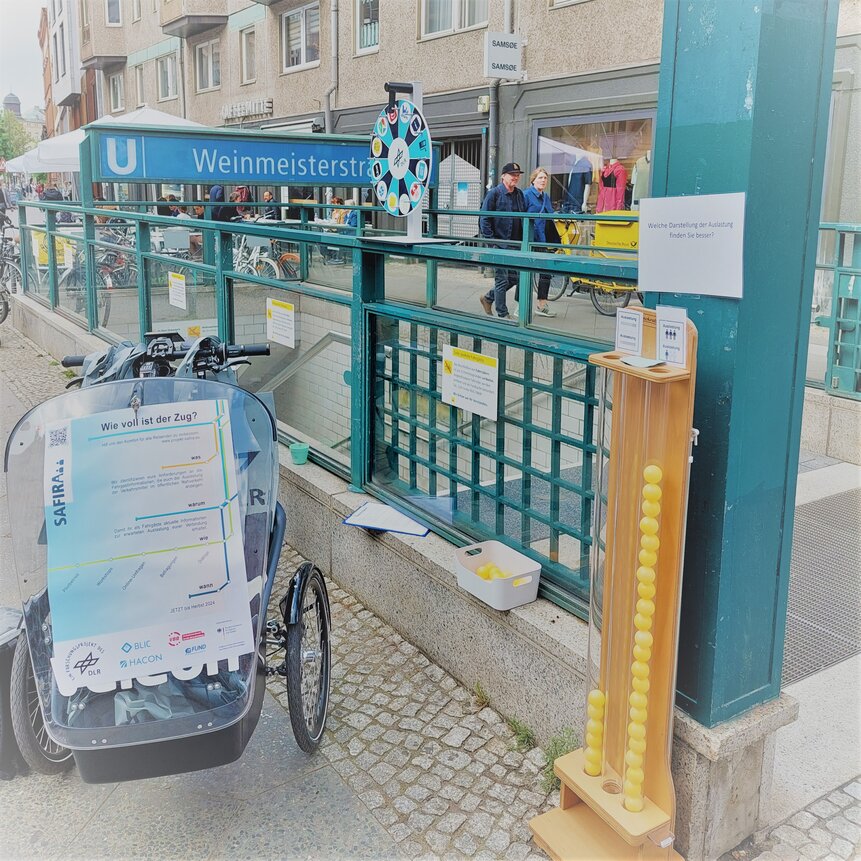 Lastenrad, Glücksrad und Abstimmungssäule vor der U-Bahn Station Weinmeisterstraße