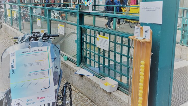 Lastenrad, Glücksrad und Abstimmungssäule vor der U-Bahn Station Weinmeisterstraße